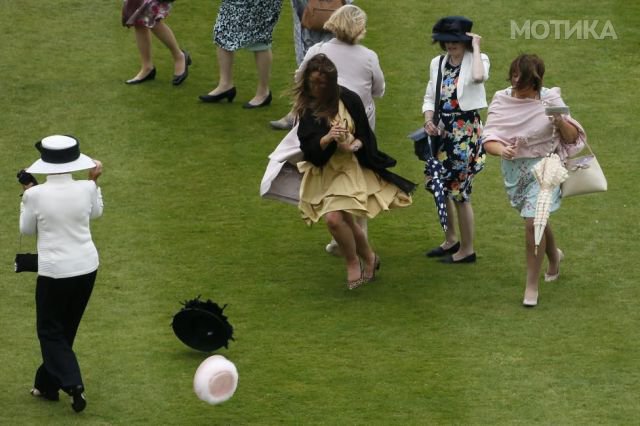 Ladies run after their hats during strong winds at a garden party at Buckingham Palace in central London