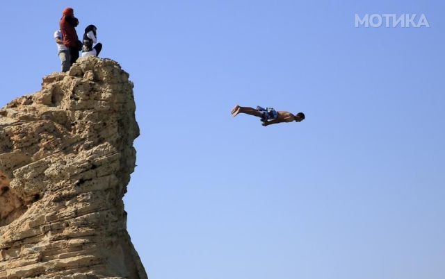 Visitors react on the rock as a man jumps into the water, above Cleopatra's Beach, on a summers day before the start of the holy month of Ramadan, which begins on June 18, at the Mediterranean city of Marsa Matrouh